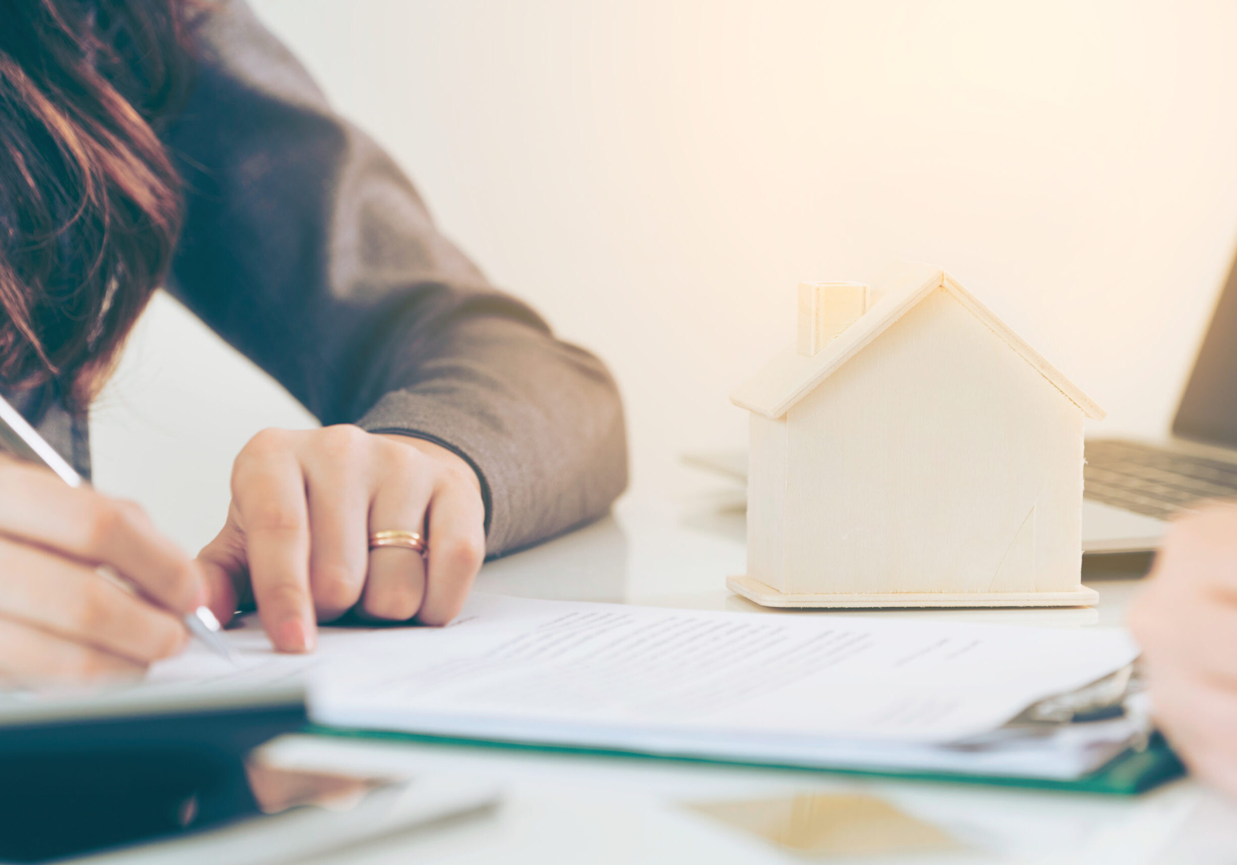 Client signs document regarding real estate activity next to lawyer or real estate agent sitting at office desk. Business concept of selling and buying house.